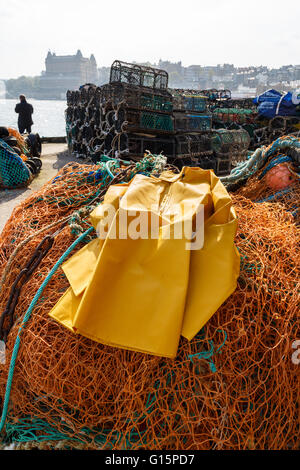 Der trawlerman schützende oilskin Kittel, kommerziellen Fischernetzen und Hummer Töpfe in den Hafen. man angeln. Stockfoto