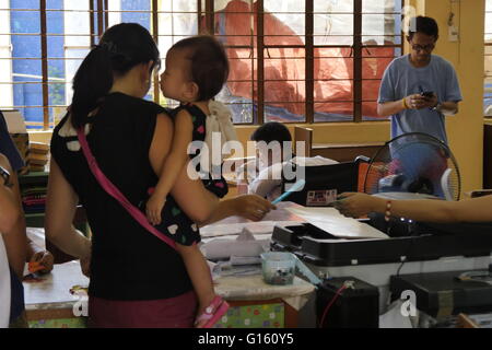 Mandaluyong, Philippinen. 9. Mai 2016. Eine Mutter kam zu stimmen, während sie ihr Kind zur gleichen Zeit trägt, über die eine Person mit Behinderung bereits abstimmen wird. © George Buid/Pacific Press/Alamy Live-Nachrichten Stockfoto