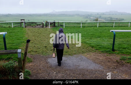 Brighton, UK. 10. Mai 2016. Eine Frau kreuzt Brighton Racecourse, als sie im Regen Spaziergänge, heute Morgen zu arbeiten, wie nasses Wetter ganz südlichen Großbritannien fegt, während Schottland heiß und sonnig Credit bleibt: Simon Dack/Alamy Live News Stockfoto