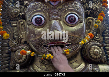 Lalitpur, Nepal. 10. Mai 2016. Ein Anhänger legt seine Hand auf das Idol der Gott Bhairav während Rato Macchindranath Festival in Lalitpur, Nepal, 10. Mai 2016. Der Hindu Legende ist der Gott des Regens Rato Machhindranath genannt. Das monatelange Rato Machhindranath Festival beginnt mit dem Bau der Wagen in Pulchowk und endet mit dem Bhoto Jatra-Festival in Jawalakhel Patan. Es wird von Buddhisten und Hindus der Newar Gemeinschaft gefeiert, mit Streitwagen zu verschiedenen Orten in der Stadt Patan in der Hoffnung auf gute Regen und Wohlstand. Bildnachweis: Pratap Thapa/Xinhua/Alamy Live Stockfoto