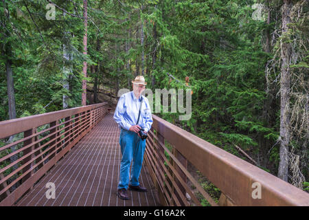 Gesunden aktiven Senior männlichen Touristen mit Kamera auf einer Brücke im Wald. Kopieren Sie Raum. Stockfoto