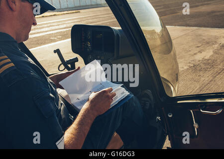 Männliche Piloten sitzen in den Hubschrauber und einem manuellen Buch vor dem Flug Stockfoto