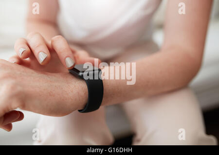 Closeup Aufnahme des kaukasischen weibliche Überprüfung Zeit auf ihrem smart-Uhr. Armbanduhr und Hände im Fokus. Stockfoto