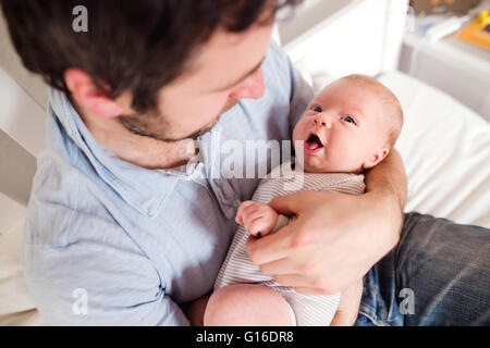 Junger Vater hält seinen neugeborenen Sohn, nach Hause Schlafzimmer Stockfoto