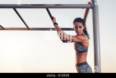 Porträt von Fit Frau Training im Freien auf Klettergerüst. Sportliche Frau mit Outdoor-Sportgeräte für Sporttraining. COP Stockfoto