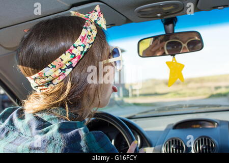 Junge Frau ein Auto zu fahren und sich mit Blick auf den Spiegel Stockfoto