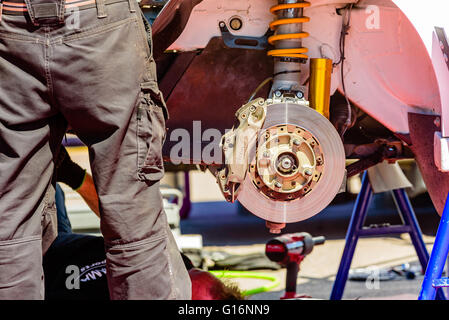 Emmaboda, Schweden - 7. Mai 2016: 41. Süd Schweden-Rallye in Service-Depot. Bremsscheibe und Bein eines Mechanikers daneben. Stockfoto