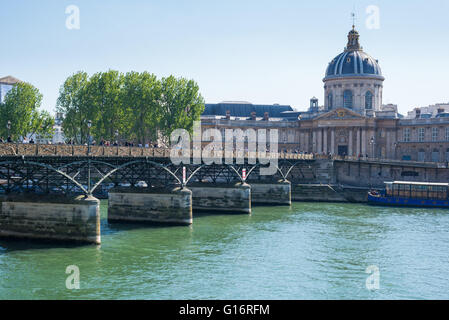 Fußgänger auf der Pont des Arts, Paris, ist es Geländer in Vorhängeschlösser abgedeckt. Institut de France im Hintergrund. Stockfoto