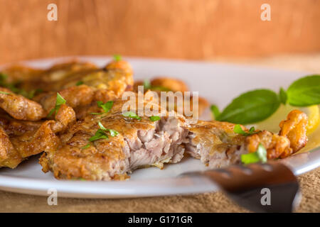 Gebratenes Schweinefleisch Gehirn mit Zitrone und Kräutern auf weißen Teller Essen Stockfoto