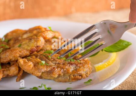 Gebratenes Schweinefleisch Gehirn mit Zitrone und Kräutern auf weißen Teller Essen Stockfoto