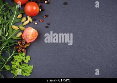 Vielzahl von frischen Kräutern, Tomaten und Gewürzen dunklen Schiefer mit textfreiraum Hintergrund Stockfoto