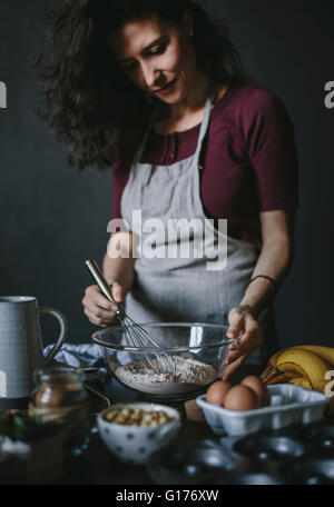Eine Frau ist, schlagen die trockenen Zutaten für Bananen Brot Donuts und von vorne fotografiert. Stockfoto