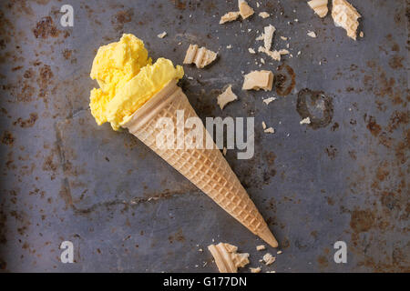 Hausgemachte Mango Eis Waffelhörnchen mit Wafer Krümel über rostiges Metall strukturierten Hintergrund. Ansicht von oben Stockfoto