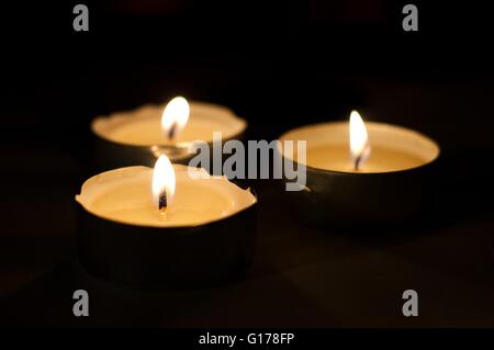 Drei brennende Teelichter auf schwarzem Hintergrund. Horizontales Bild Stockfoto