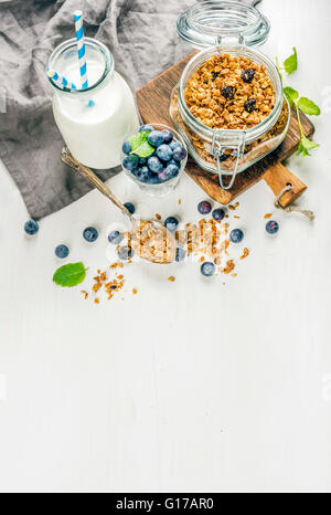 Gesundes Frühstück ruhigen. Hausgemachtem Müsli in offenen Glasflasche Glas, Milch oder Joghurt, Blaubeeren und Minze auf weißem Holz ba Stockfoto