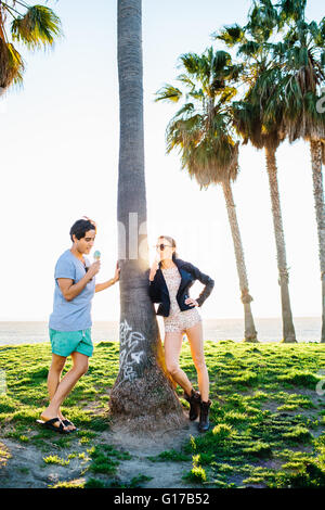 Junges Paar gelehnt sonnenbeschienenen Palme essen Eiscreme-Kegel, Venice Beach, Kalifornien, USA Stockfoto