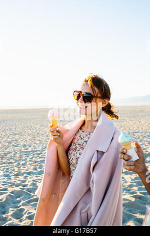 Stilvolle junge Frau mit Freund essen Eiscreme-Kegel spazieren am Strand, Venice Beach, Kalifornien, USA Stockfoto