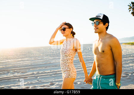 Junges Paar tragen Badehose und Shorts ein Spaziergang am Strand von Venice Beach, Kalifornien, USA Stockfoto