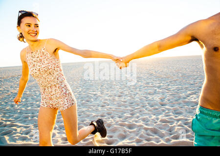 Junges Paar tragen Badehose und Shorts, die Hand in Hand am Strand von Venice Beach, Kalifornien, USA Stockfoto