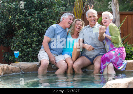 Gruppe von Senioren Lachen Fotos in Smartphone am pool