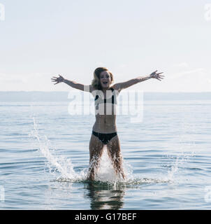 Teenager-Mädchen stehen im Meer, Spritzwasser Stockfoto
