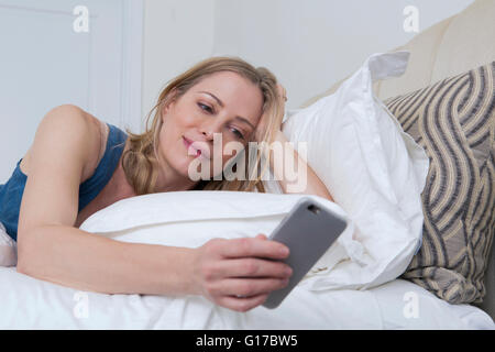 Frau im Bett und Las Smartphone Texte Stockfoto