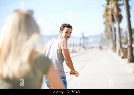 Mann im Rückblick auf Freundin während Radfahren am Venice Beach, Los Angeles, Kalifornien, USA Stockfoto