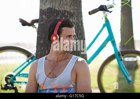 Männliche Radfahrer sitzen Kopfhörer Musikhören am Venice Beach, Los Angeles, Kalifornien, USA Stockfoto