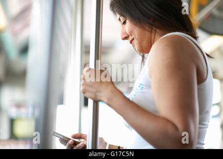 Frau stehend auf Bus lesen Smartphone Texte, Los Angeles, Kalifornien, USA Stockfoto