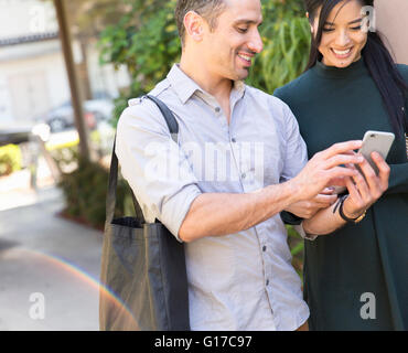 Paar in der Straße mit Blick auf das Smartphone zu Lächeln Stockfoto