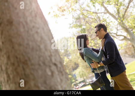 Paar im Park von Angesicht zu Angesicht umarmt und lächelnd Stockfoto