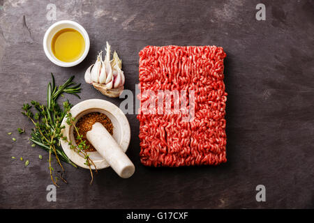 Hackfleisch / Faschiertes auf Stein Schiefer Hintergrund mit Pfeffer, Knoblauch und Kräutern Stockfoto