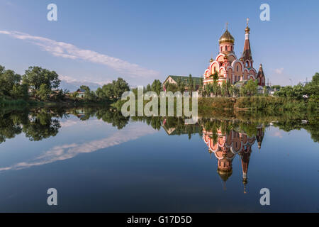 Russisch-orthodoxe Kirche in Almaty, Kasachstan, auch bekannt als Kirche der Erhöhung des Heiligen Kreuzes und dessen Spiegelbild im Wasser. Stockfoto