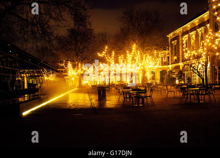 leere Nacht Restaurant, viele Tische und Stühle mit niemand, magische Lichterketten an Bäumen wie Weihnachten, Luxus-lifestyle Stockfoto