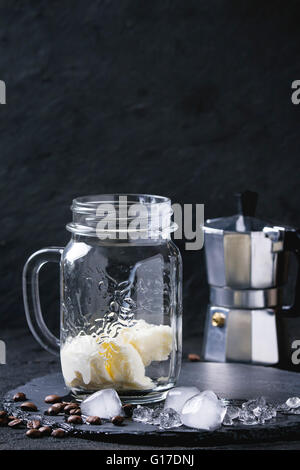 Mason Glas mit Eis Eis Kaffee, serviert mit Kaffeebohnen, Kaffee Topf und Eiswürfel auf Schiefer an Bord Ov Stockfoto