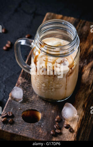 Mason Glas Eis Kaffee mit Eis und Schokolade-Sauce, serviert mit Kaffeebohnen und Eiswürfel auf Holz hacken Wildschwein Stockfoto