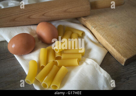 Italienisches Essen. Nudeln (Rigatoni) mit Eiern auf Holztisch bei schwachem Licht Stockfoto