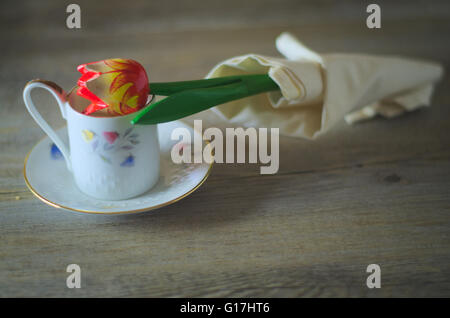 Hölzerne Blume. Rote Tulpe in eine Kaffeetasse. Friedliche Tageslicht über einen rustikalen Tisch Stockfoto