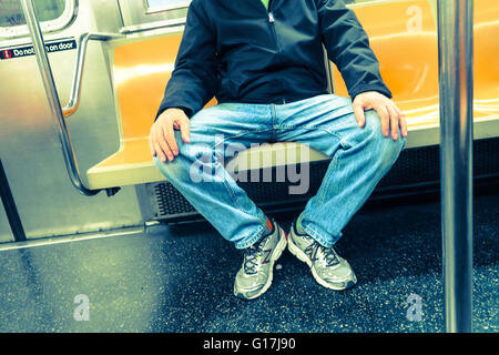 Mann in Beschlag nehmen mehr als einen Sitz (man-Verteilung) auf New Yorker U-Bahn (tube), NYC, USA Stockfoto