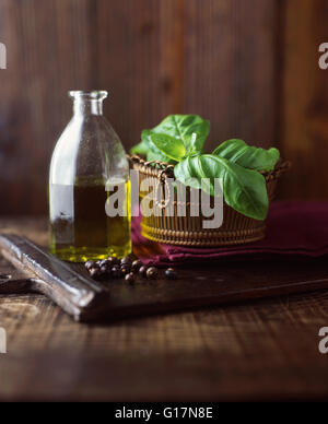 Extra natives Olivenöl, Basilikum und Wacholder Beeren auf Schneidbrett aus Holz Stockfoto