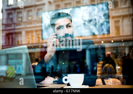 Geschäftsmann, sitzen im Café Fensterplatz mit Laptop und smartphone Stockfoto