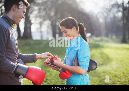 Junger Mann und Frau setzen auf Boxhandschuhe für Training im park Stockfoto