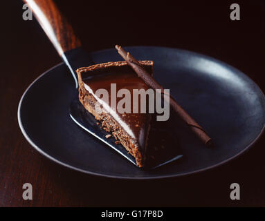 Stück Schokolade mit Tortenheber auf Platte Stockfoto