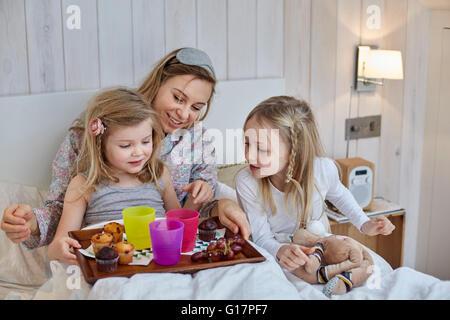 Mutter und Töchter mit Frühstück im Bett Stockfoto