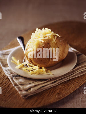 Ofenkartoffel mit geriebenen Cheddar-Käse auf Holzbrett Stockfoto