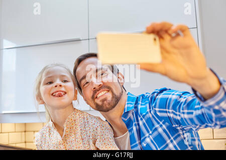 Vater und Tochter nehmen Selfie in Küche Stockfoto