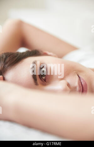 Porträt der schönen jungen Frau auf Bett liegend hautnah