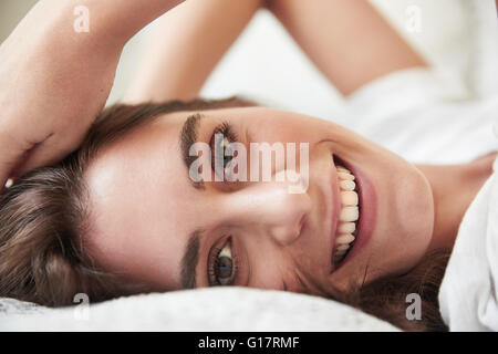 Porträt der schönen jungen Frau auf Bett liegend hautnah