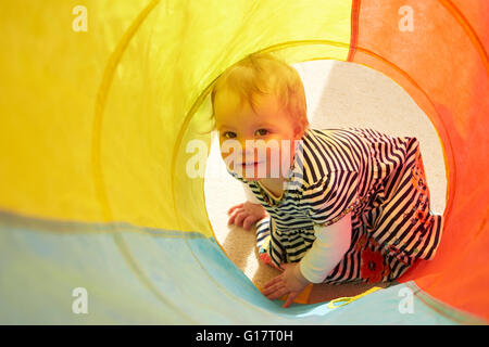 Porträt von Babymädchen in mehrfarbigen Tunnel kriechen Stockfoto
