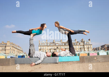 Männer und Frauen üben akrobatische Yoga an Wand am Brighton beach Stockfoto